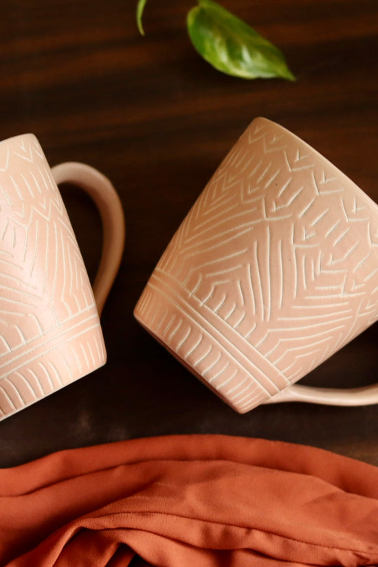 Blush pink carved coffee mug laying on wooden surface