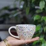 Handmade colorful polka coffee mug in hand