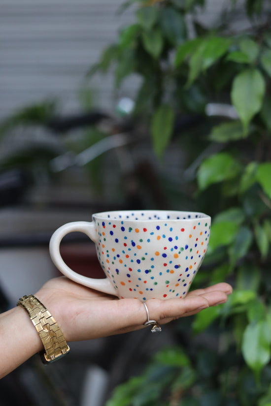 Handmade colorful polka coffee mug in hand
