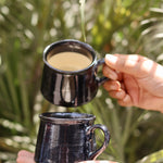 Two black tea cup with tea in a hand