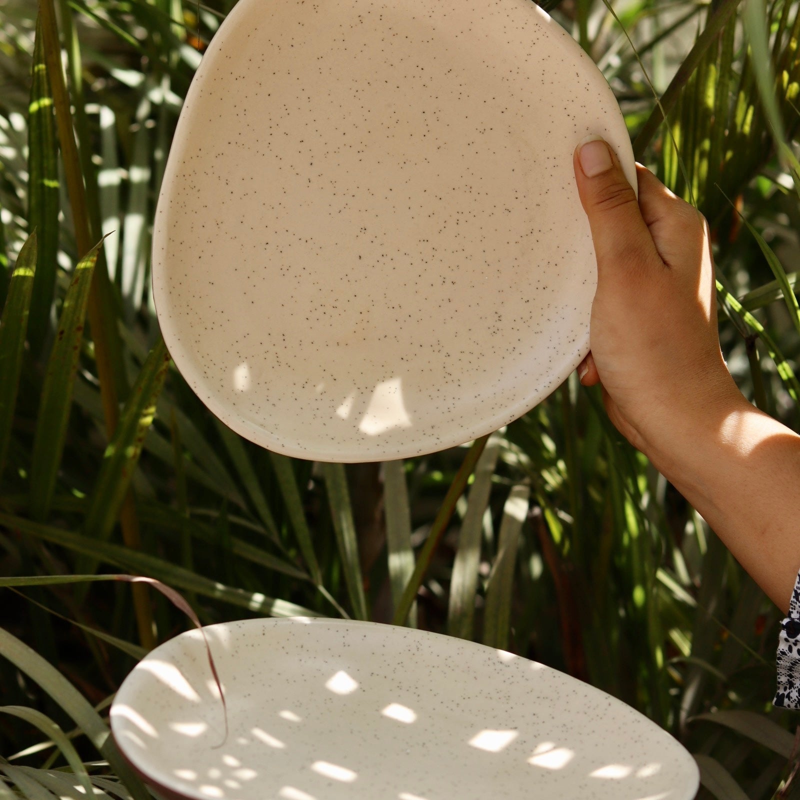 Handmade ceramic white speckled platters in hand 