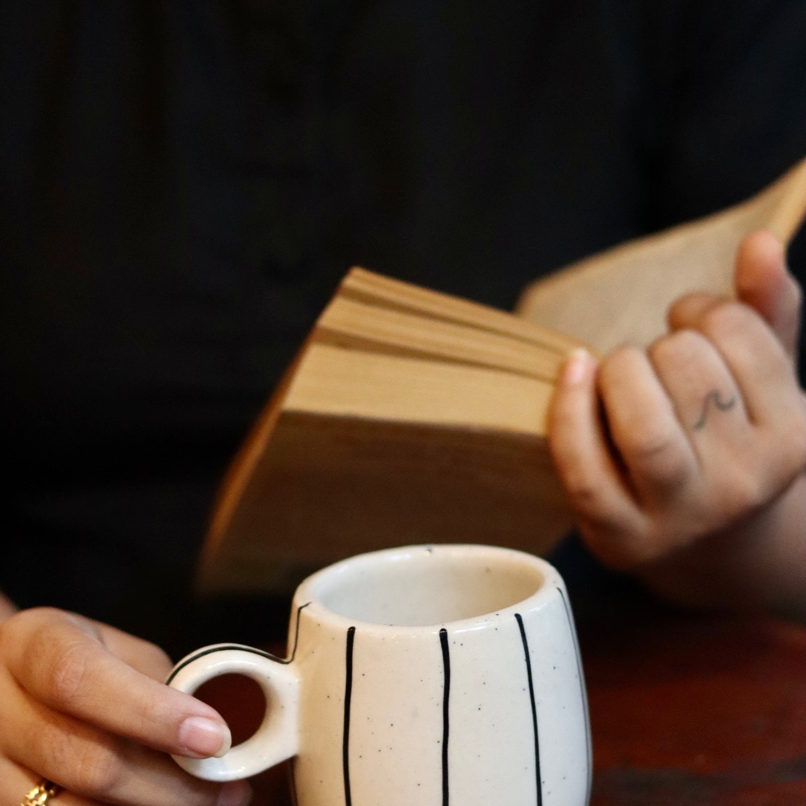 Someone reading a book with drinking tea in black lined mug