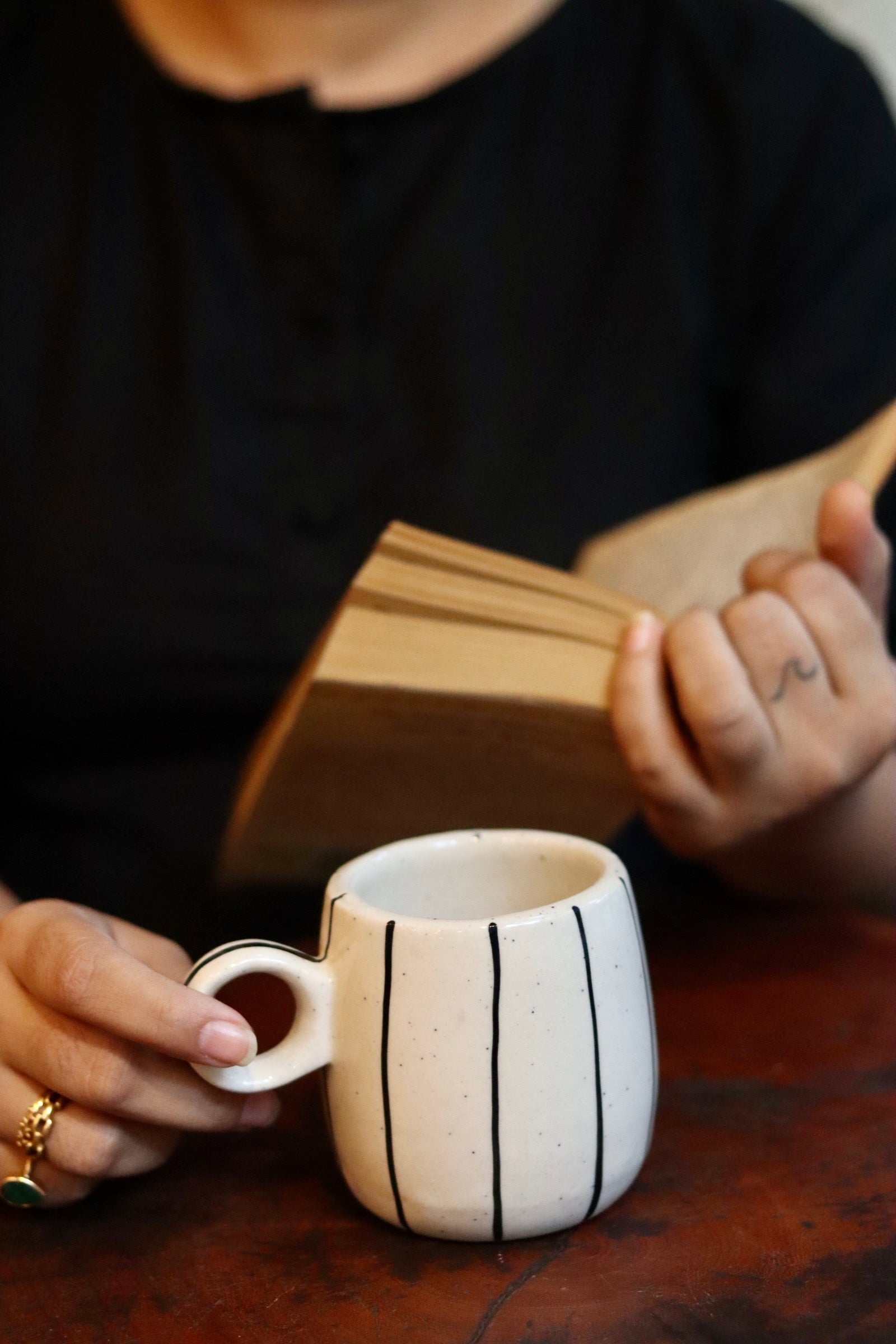 Someone reading a book with drinking tea in black lined mug