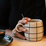 Black checkered coffee mug in a hand