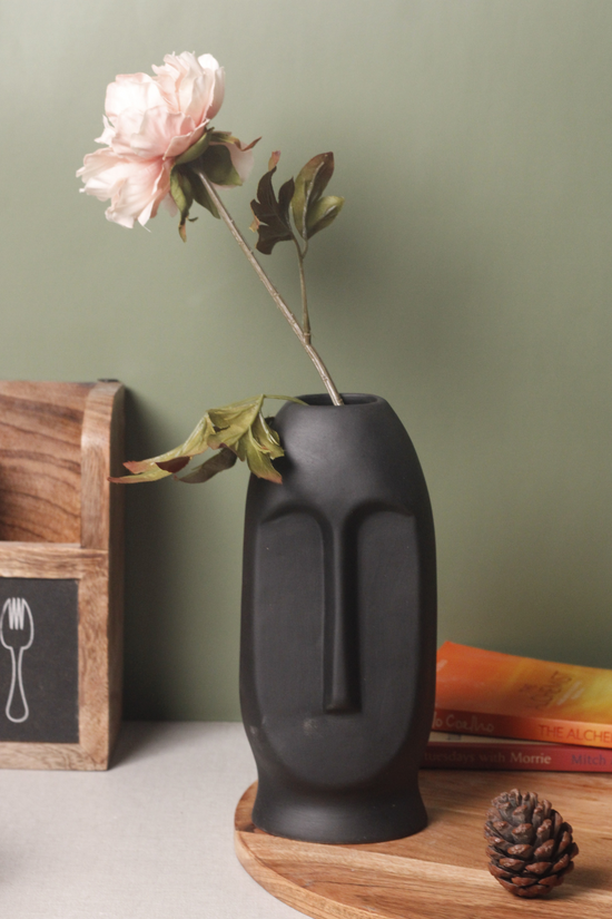 Black face vase with flower on a wooden surface