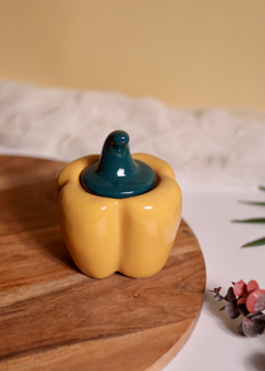 Yellow bell pepper jar with green lid on a wooden surface