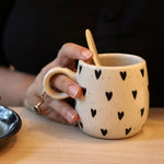 Black heart cuddle mug in a hand