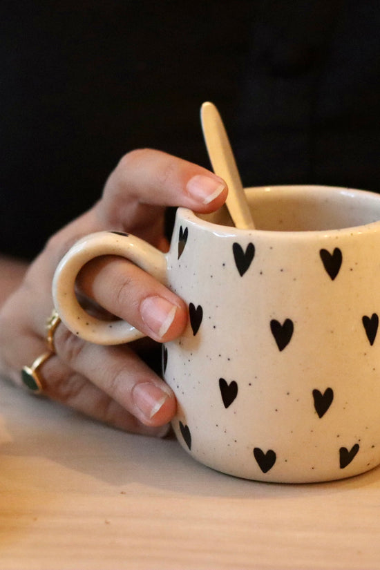 Black heart cuddle mug in a hand