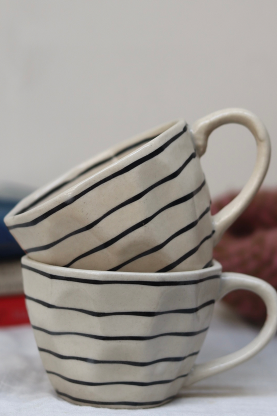 Two black lined handmade coffee mugs on each other